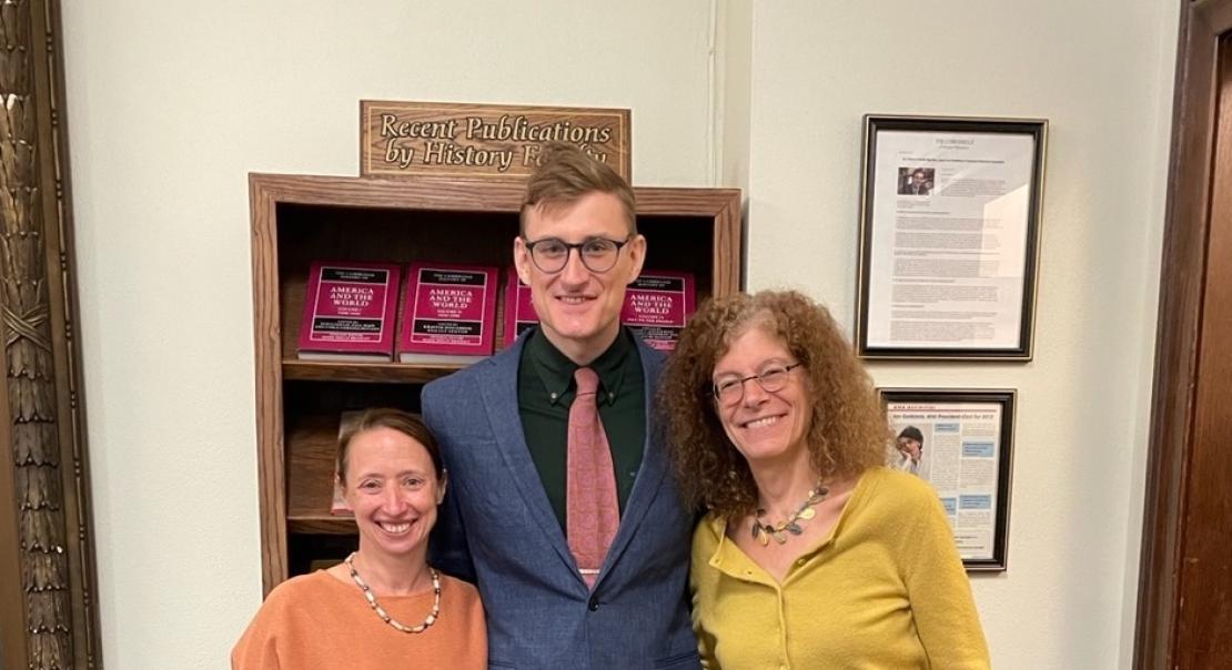 three people standing in front of a bookshelf